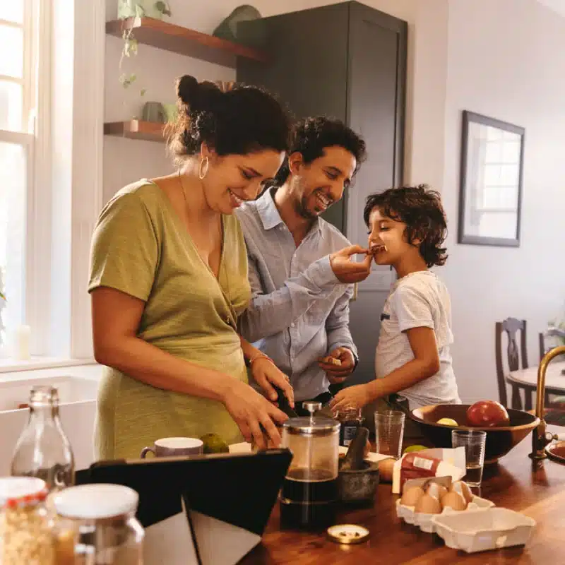 A family of three cheerfully preparing a meal.