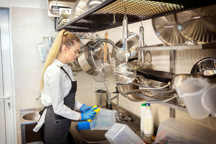 Young woman cleaning dishes in a restaurant
